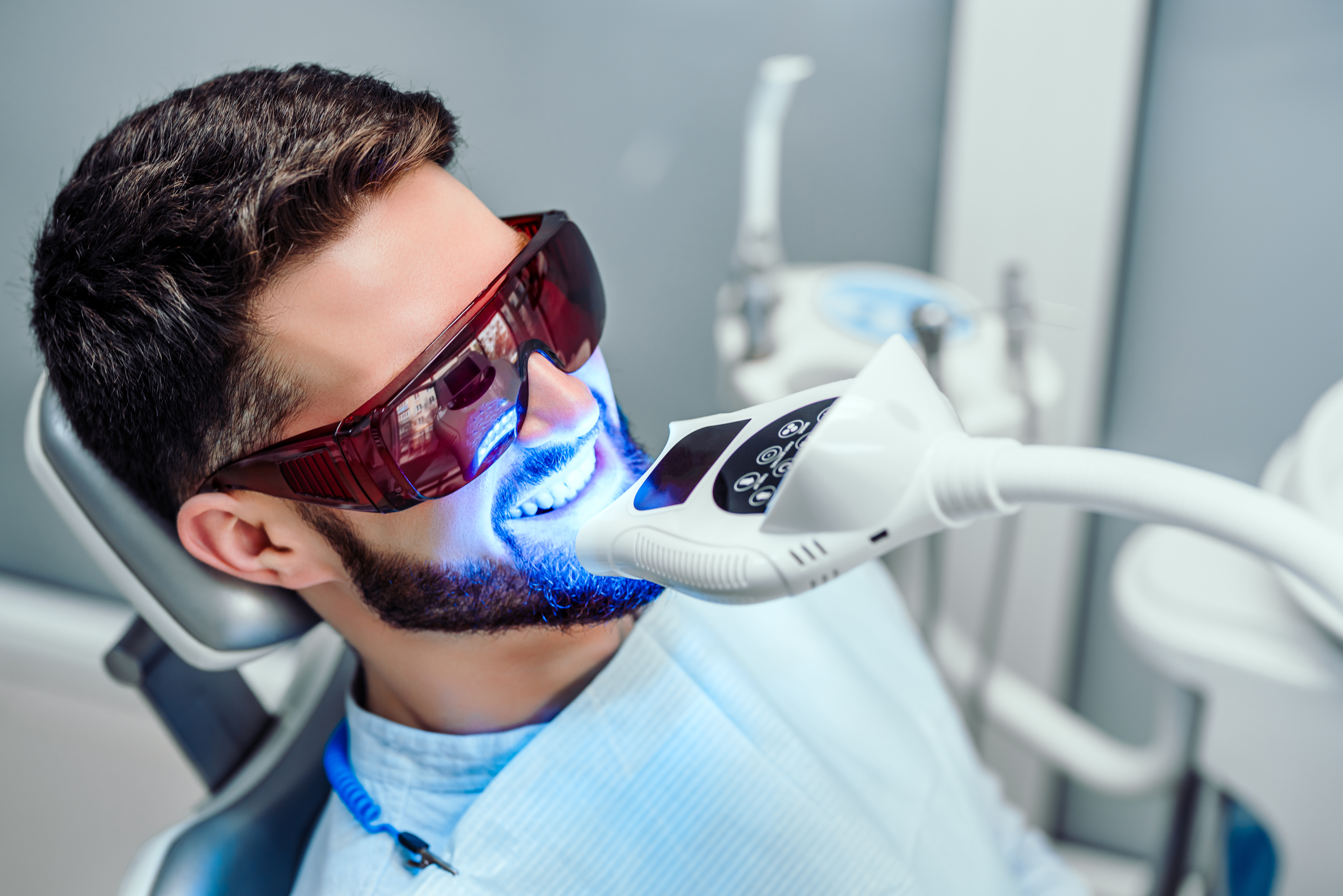 man receiving teeth whitening treatment in dental office